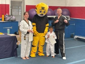 Star Tiger Student being awarded a new belt, with Tiger Mascot and Instructors