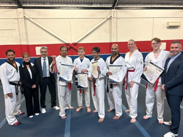 A lineup of Students with Master Cesar, awarded their red black tags and black belts, holding their certificates